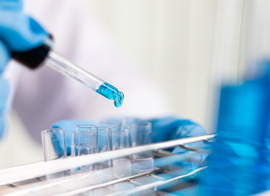 Scientist using pipette to transfer blue liquid into test tubes for SeraNovo NanoGlass formulation technology